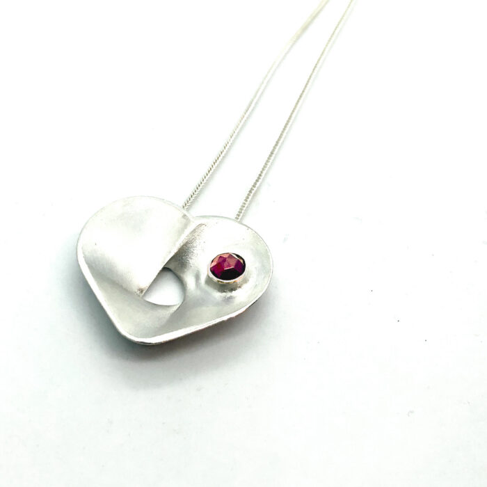 Hõbedast südamekujuline kaelaehe kiviga, vääriskivi punane granaat. Süda 400mm, kett 700mm. Eesti disain.